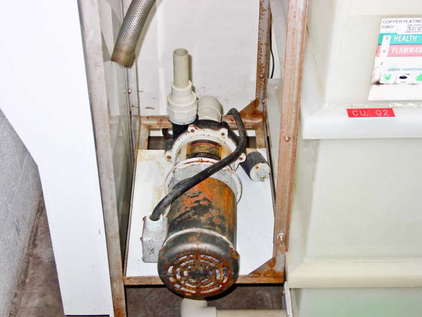 Iwaki Walchem MDH-400CV5 magnetic drive pump mounted in lower cabinet enclosure — heavily corroded exterior with chemical residue visible