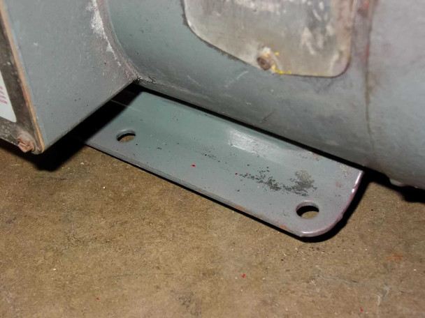 Baldor motor base foot/mounting bracket – gray painted steel foot plate with two mounting holes, surface dirt and minor rust