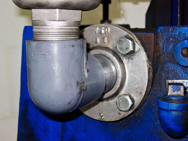Inlet flange detail on Tuthill KTC112 vacuum pump — large flanged elbow fitting with LASCO PVC pipe adapter and Kinney label