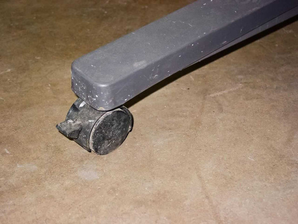 Close-up of one rolling caster showing wear and minor damage to caster wheel