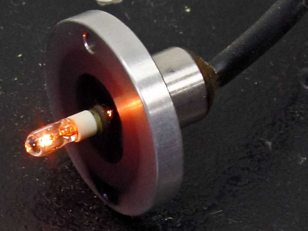 Bausch & Lomb optical stand — close-up of illuminated incandescent point source lamp in circular aluminum mount, glowing orange on black base surface