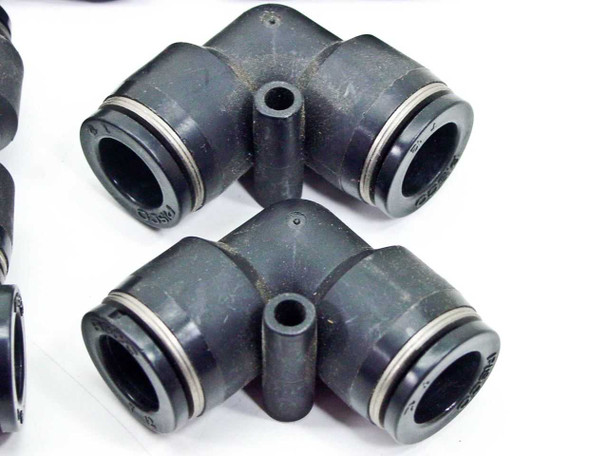 Two black SMC 90-degree elbow push-to-connect fittings showing port openings and collet ring detail