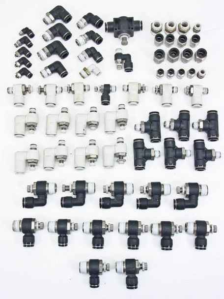 SMC pneumatic push-in fittings lot — full overhead view showing elbows, tees, straights, speed controllers, and straight connectors in black and white