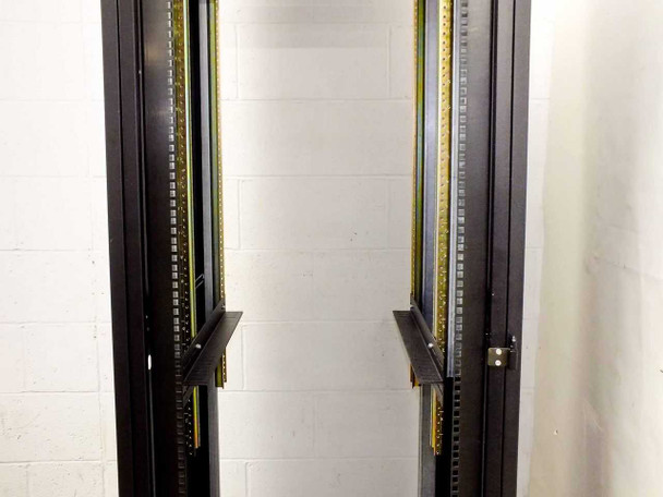 Dual vertical rail close-up inside 37U rackmount cabinet showing gold EIA-standard mounting rails and cable management channel