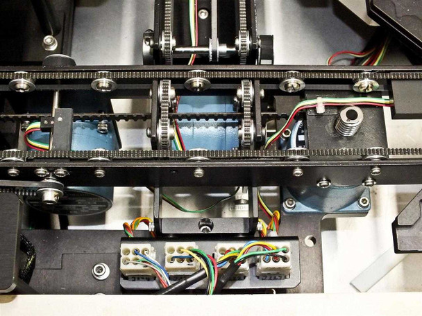 Close-up of P5NMS belt-driven X/Y stage stepper motor assembly showing toothed belts, pulleys, and multi-color wiring harness