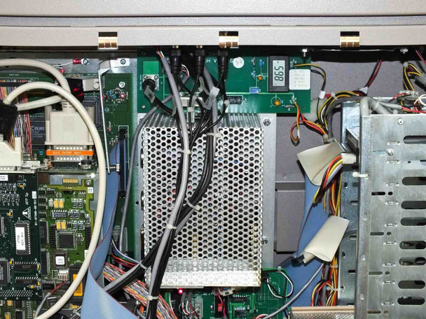 Interior close-up – internal power supply modules with perforated enclosures, wiring harnesses, ribbon cable, and additional PCBs