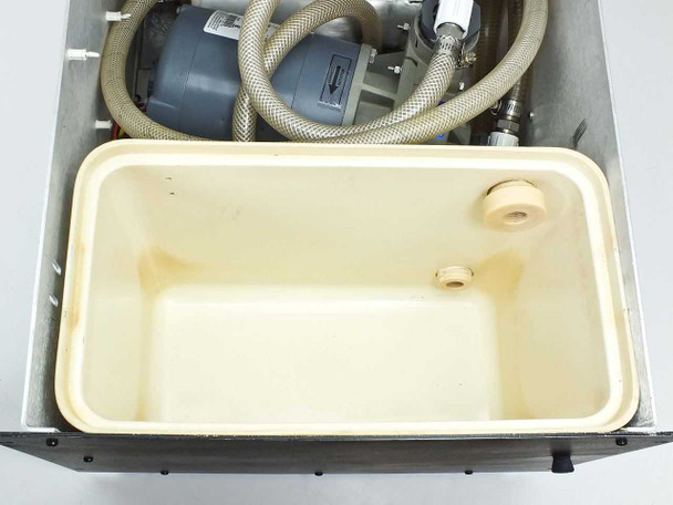 Top-down close-up of plastic water reservoir tray inside rackmount cooler chassis showing drain fittings