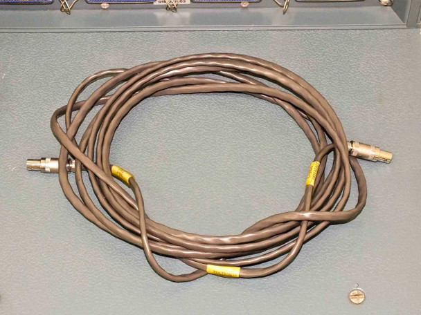 Coiled system cable with yellow-tagged Lemo/circular connectors on both ends — HNVS system interconnect cable laid on blue equipment chassis