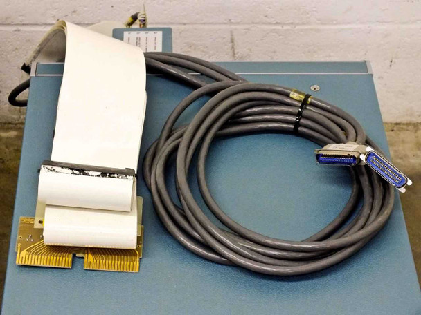 Cables and board accessories laid on top of blue chassis — includes flat ribbon cable assembly with gold-finger edge connector board, and a coiled cable with Centronics 50-pin connector