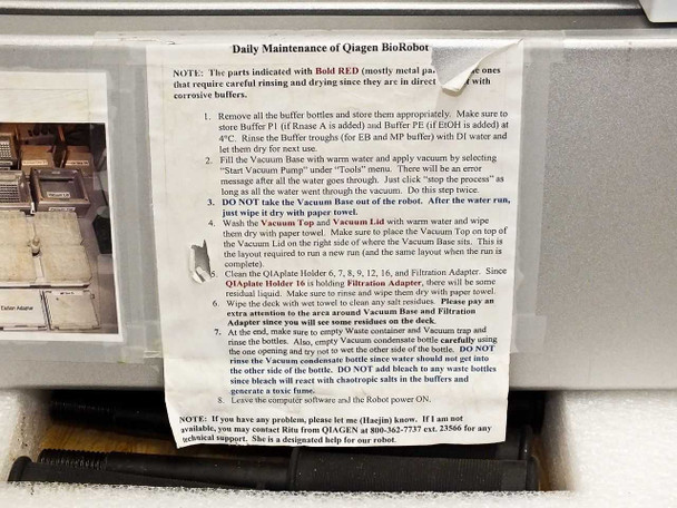 Daily Maintenance instruction sheet for Qiagen BioRobot affixed to unit, detailing buffer preparation, vacuum base procedure, and cleaning steps
