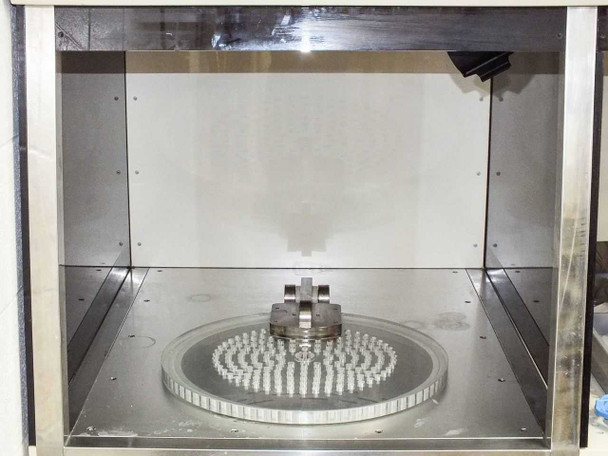 Interior left chamber showing rotating disc/wafer carrier turntable with center hub and pin array — stainless steel enclosure