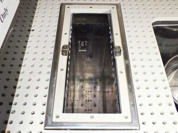 Close-up of flush-mounted rectangular ultrasonic bath tank inset into perforated stainless steel work surface, open and empty