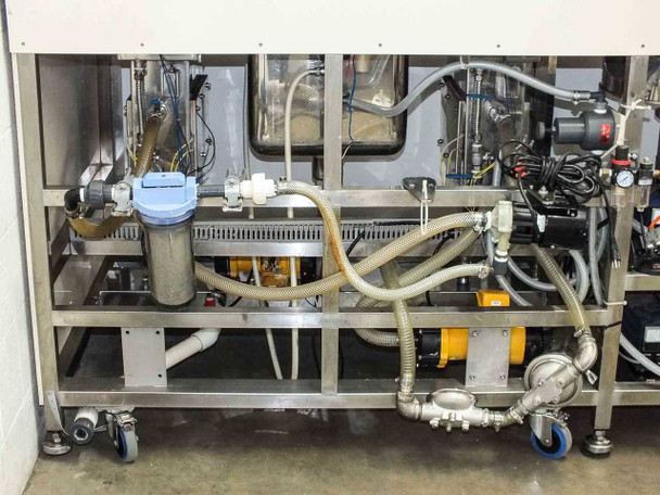 Rear under-bench detail showing water filtration plumbing with blue Pacific filter housing, yellow pump, solenoid valves, and hose connections