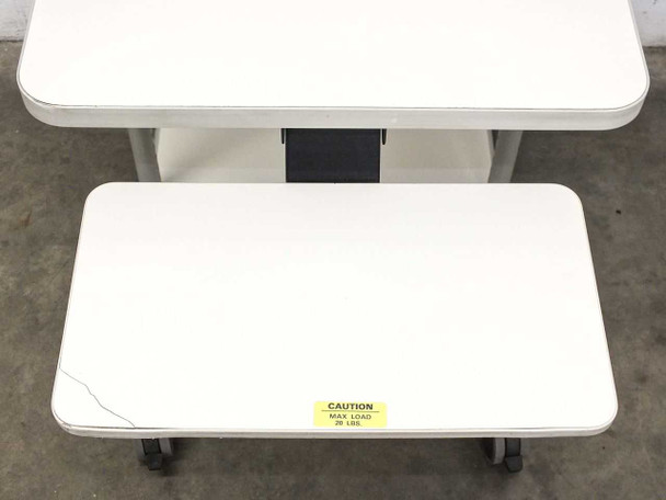 Keyboard shelf and bottom platform view showing caution label reading MAX LOAD 25 LBS and locking caster wheels