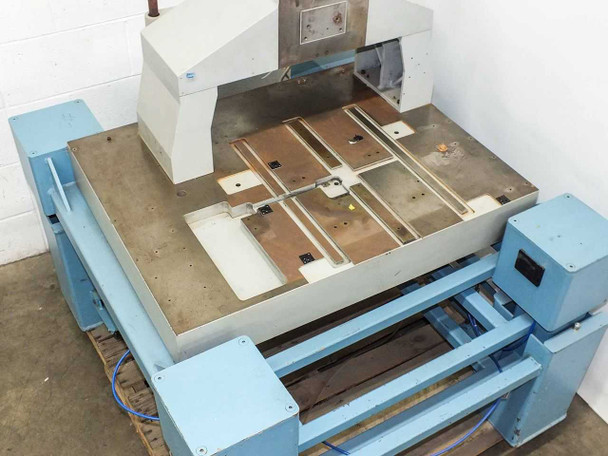 Elevated view from front-right showing full table surface with stage plates, column tower, and blue frame assembly