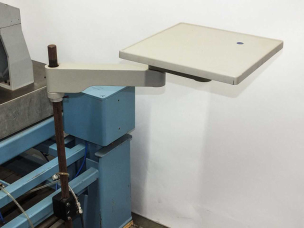 Side-mounted articulating arm with flat white work shelf attached to blue isolation table frame