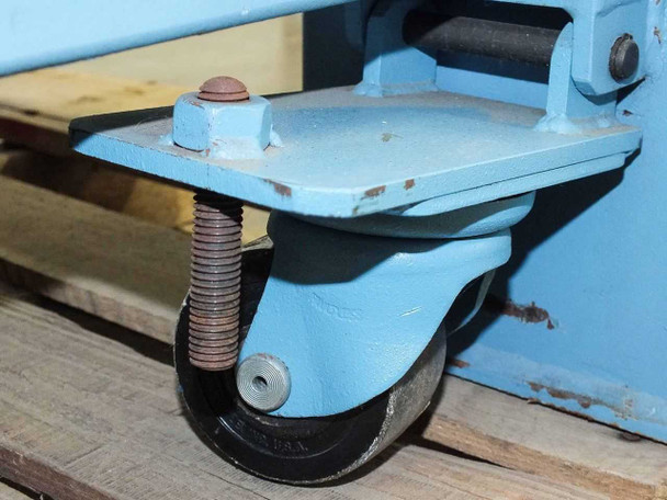 Heavy-duty locking castor wheel on blue steel frame base showing spring-loaded leveling pad and swivel mount