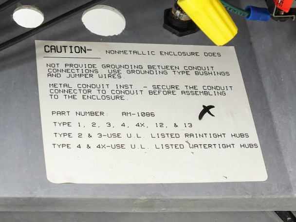 Caution label inside enclosure lid showing part number AM-1086, enclosure type ratings 1 2 3 4 4X 12 13, and grounding instructions