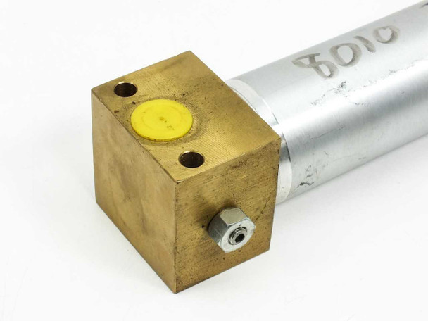 Close-up of cap-end brass block showing yellow port plug, NPT port fitting, and mounting holes