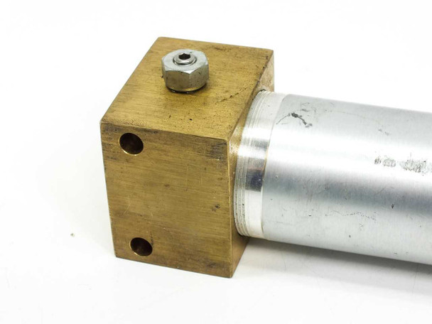 Close-up of cap-end brass block opposite side showing NPT port fitting and aluminum barrel connection