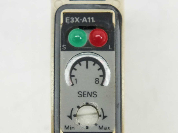 Close-up of Omron E3X-A11 top panel showing green and red LEDs, 1–8 SENS rotary dial, and Min/Max sensitivity adjuster