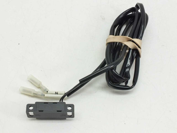 Unbranded magnetic proximity reed switch front view showing black rectangular housing with mounting bracket and bundled cable with spade connectors