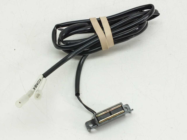 Unbranded magnetic proximity reed switch with long black lead cable bundled with tape and spade terminals visible at wire end
