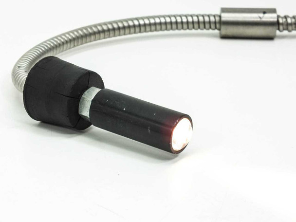 Fiber optic flex cable output tip illuminated with transmitted light glowing red, demonstrating fiber optic light transmission through the cable