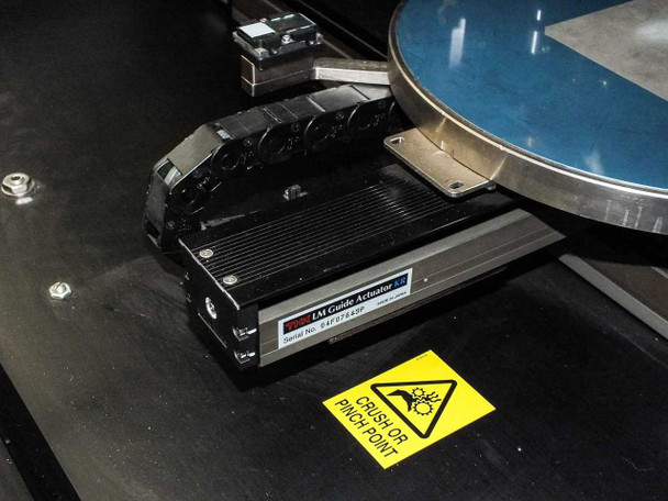 Camtek Falcon PD – IAI Guide Actuator linear stage with crush/pinch point warning label, adjacent to wafer chuck platen