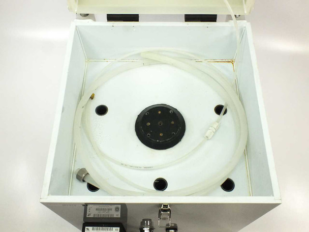 Top-down open interior view of HDPE chamber showing circular spin chuck with multi-pin connector, white HDPE coated walls, drain/feed tubing, and fittings
