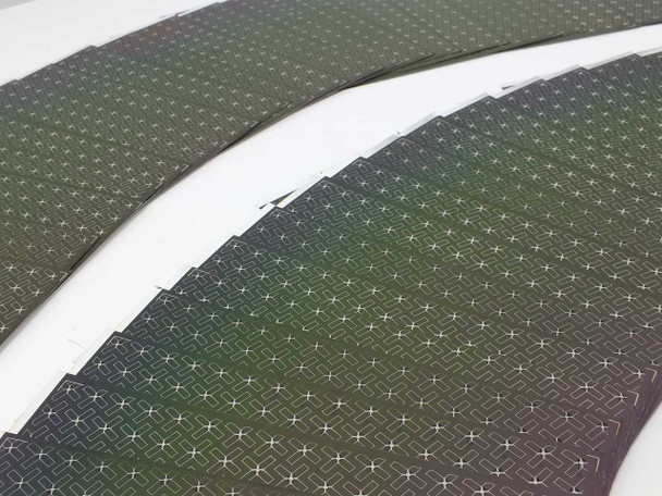 Multiple Nanosolar NanoCell CIGS cells fanned out showing iridescent color variation across the thin-film surface and MWT grid pattern