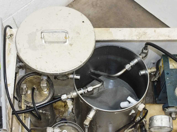 Open stainless steel container interior showing baffled bottom, fluid ports, and compression fitting connections
