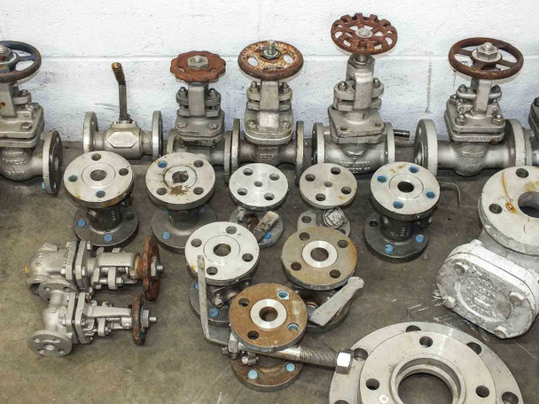 Close view of mixed stainless steel flanged gate valves and pipe flange fittings showing variety of sizes and handwheels