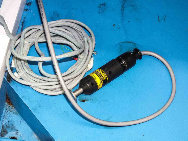 Hazardous gas sensor or detector with yellow warning label and coiled cable lying on cabinet tray
