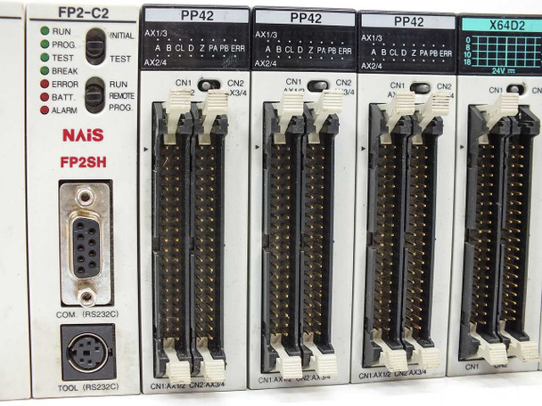 NAIS FP2-C2 CPU (FP2SH) and three PP42 positioning modules closeup — showing RUN/PROG/TEST/BREAK/ERROR/BATT/ALARM LEDs, RS-232C COM port, and CN1/CN2 ribbon connectors