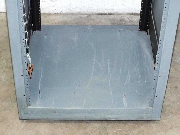 Interior floor of rackmount cabinet showing heavy gauge steel base plate with surface scratches and chain latch on left rail