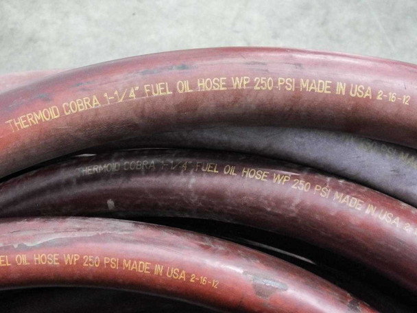 Thermoid Cobra 1-1/4" fuel oil hose close-up showing embossed text: THERMOID COBRA 1-1/4" FUEL OIL HOSE WP 250 PSI MADE IN USA 2-16-12
