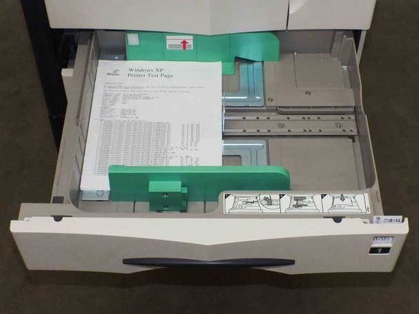 Kyocera Mita FS-9500DN paper drawer 1 open — green paper guides with Windows XP printer test page inside