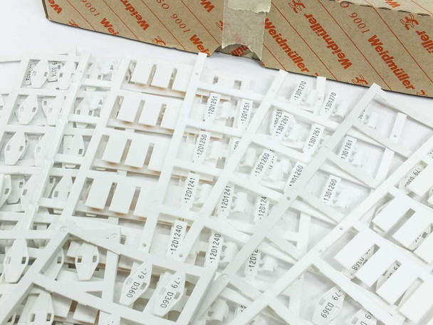 Close-up of Weidmuller white cable marker strips showing pre-printed identification numbers including 1201240, 1201241, 1301150, 1301151, and others