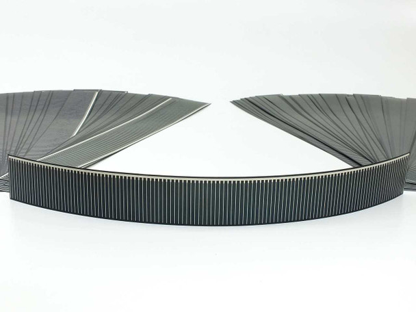 Solopower CIGS flexible solar cell strip coiled into a ring and laid flat, showing semi-flexible stainless steel backing and dark photovoltaic surface