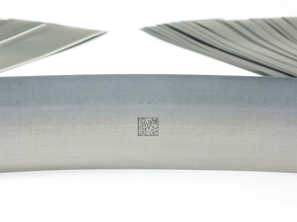Close-up of Solopower flexible stainless steel solar cell substrate showing a small laser-etched QR or data matrix code on the bare metal backing
