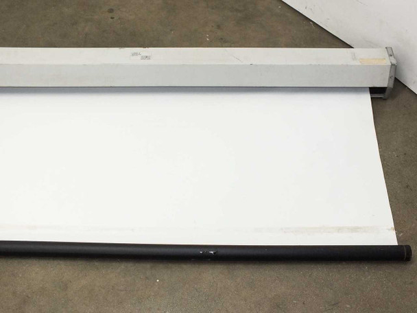 Draper LUMA2 screen partially unrolled showing white projection surface and black bottom dowel rod, aluminum housing behind
