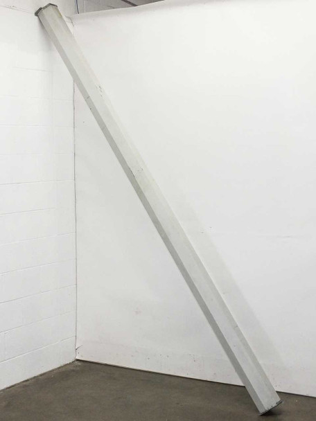 Draper LUMA2 projection screen in white aluminum housing, leaning against wall — full length side view