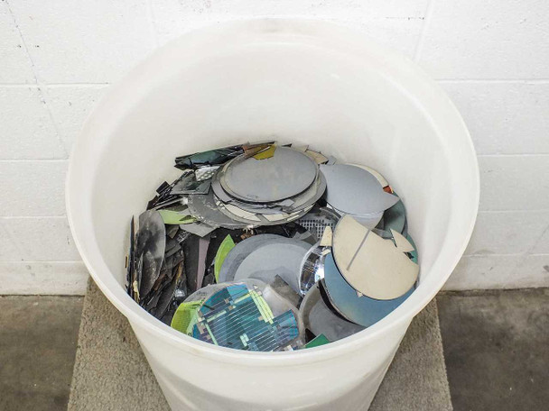 Top-down view of HDPE tank filled with assorted broken and whole silicon wafers of various sizes and colors