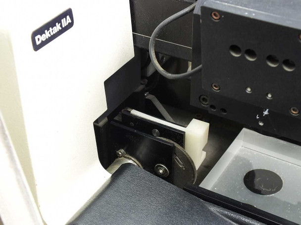 Sloan Dektak IIA scan head — close-up of stylus arm and stage mechanism showing stylus needle, spring, and sample positioning hardware; 'Dektak IIA' label visible