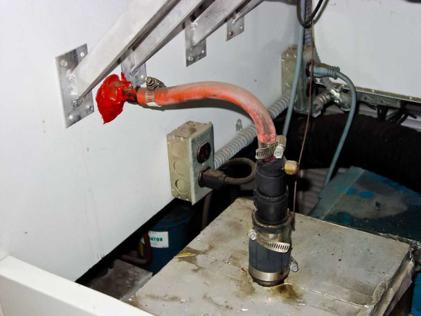 Internal water supply area showing red-handled shutoff valve, flexible hose, and drain components