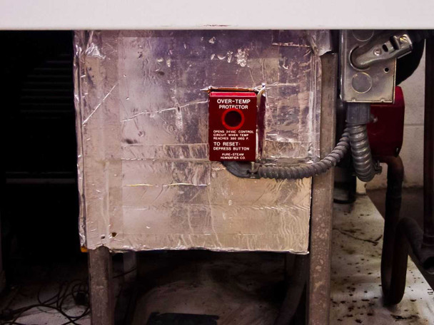 Pure-Steam Over-Temp Protector red reset button panel mounted on foil-wrapped insulated interior surface