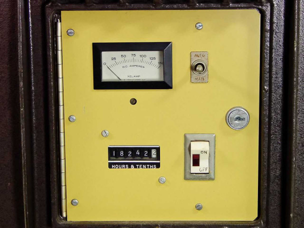 LP Associates 8510 Xelamp — front control panel close-up showing DC Amperes analog meter (0-125A scale), AUTO/MAIN toggle switch, key switch, hours-and-tenths counter reading 18242, and ON/OFF toggle switch