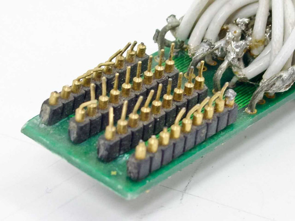 Close-up of internal PCB breakout end showing gold solder pins and multi-conductor white wire terminations