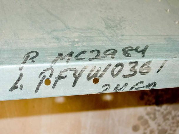 Hand-written inventory markings on sheet metal duct surface reading project reference numbers and dimension notation